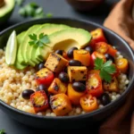 Vegan fajita bowl with couscous, grilled tofu, black beans, cherry tomatoes, avocado, and lime wedges in a black bowl.
